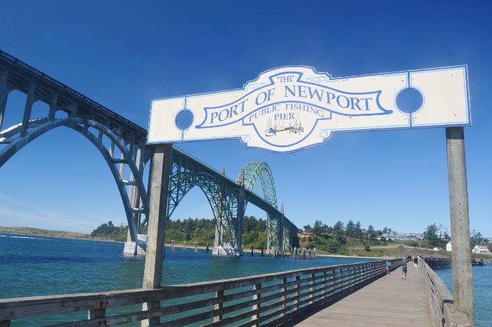 sign to the public fishing pier with the Yaquina Bay Bridge in the background